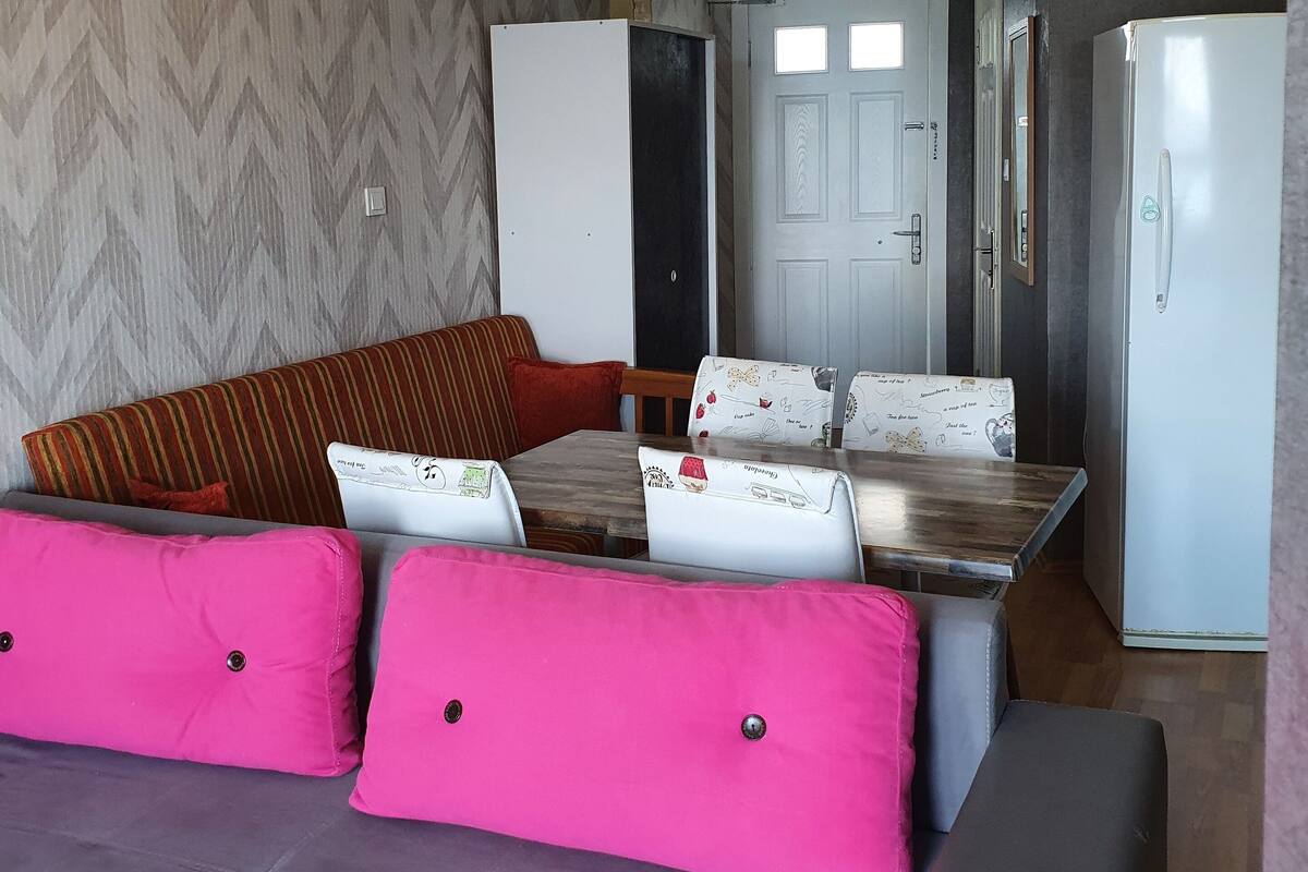 A compact living space with a sofa, a dining table, and a refrigerator.