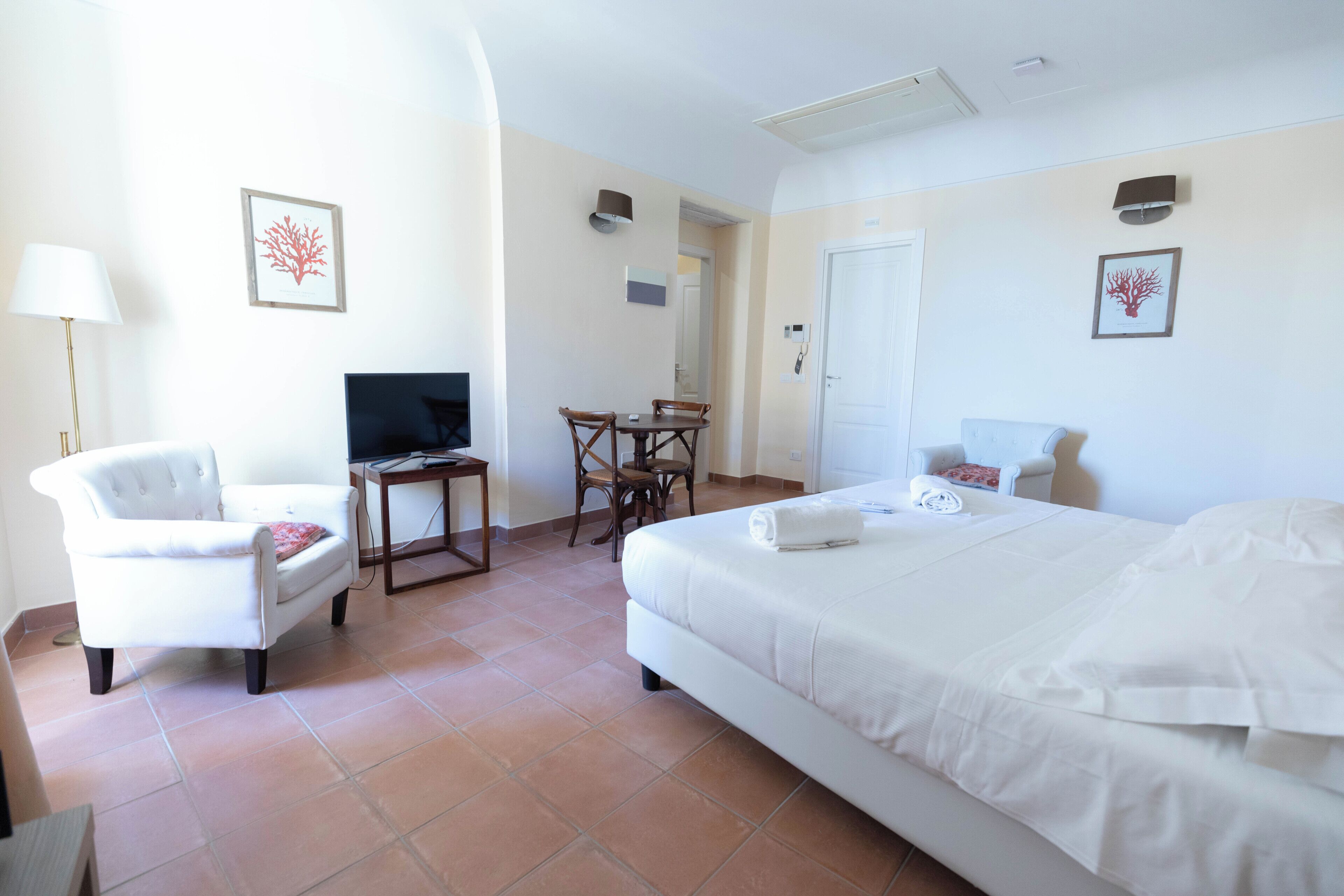 Una habitación de hotel con cama, escritorio, silla, televisor y puerta.