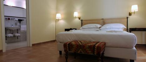 Una cama grande con cabecera de madera, dos lámparas de noche y una manta decorativa.