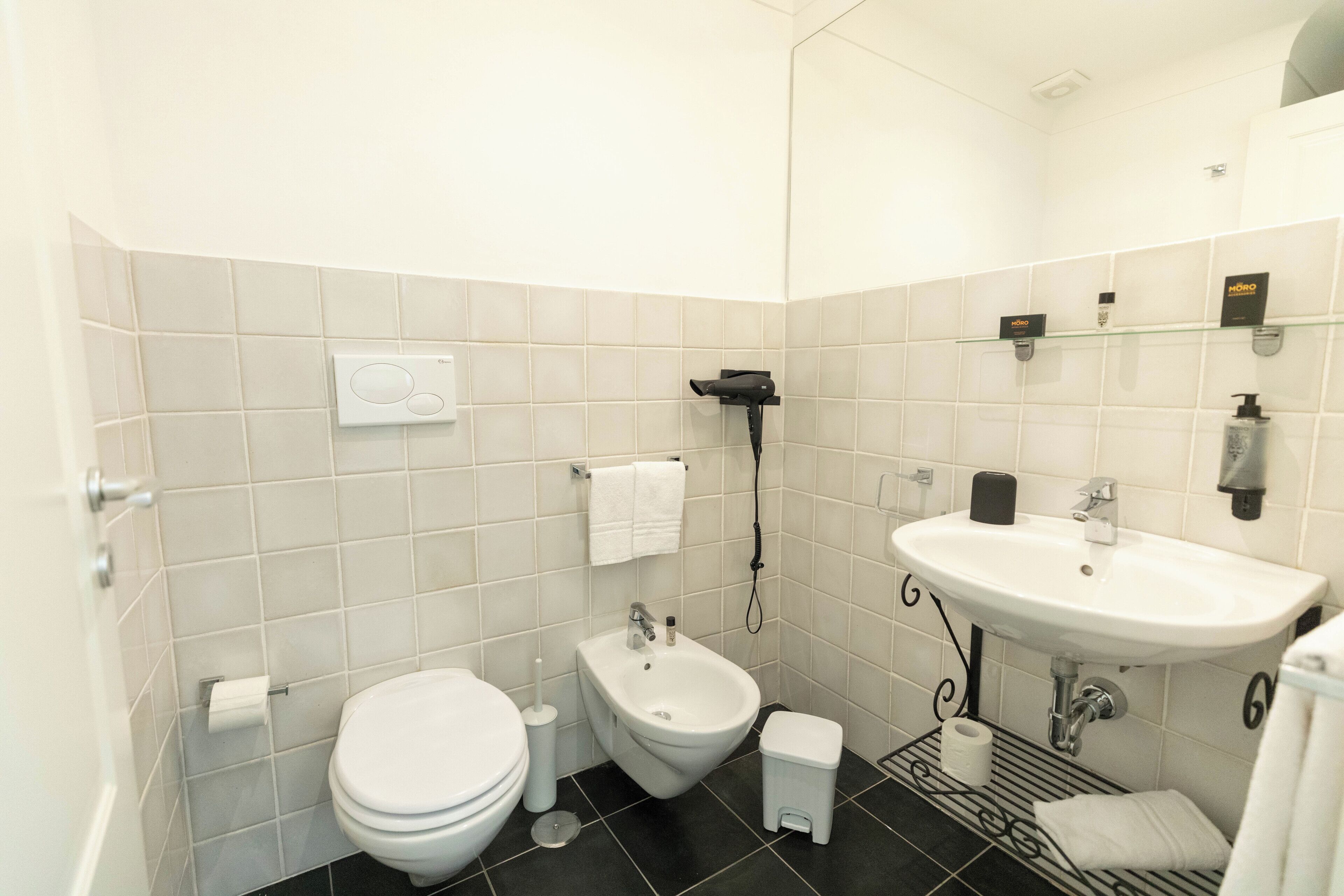 Un baño moderno con inodoro, bidé, lavamanos y toallero.