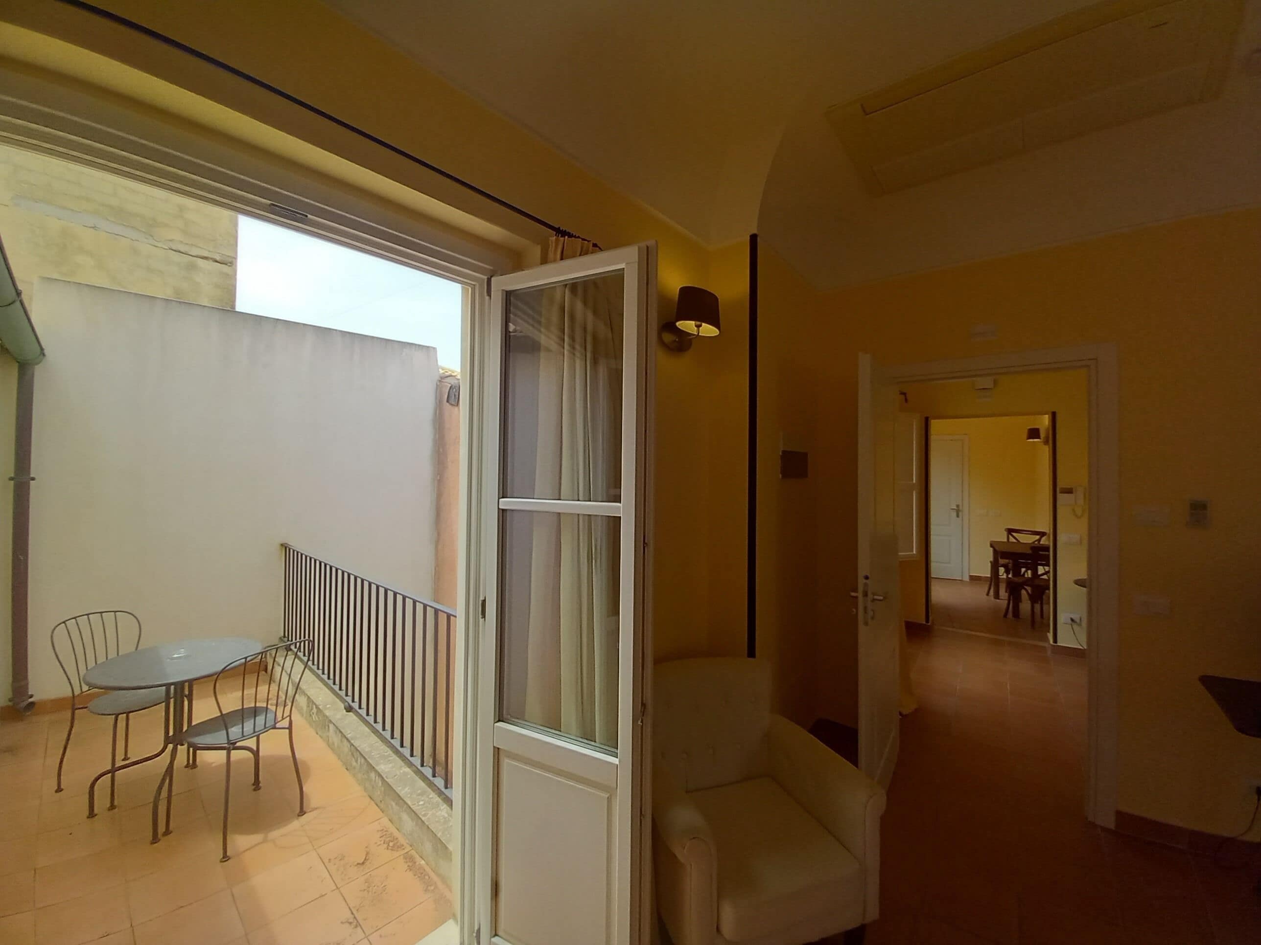 Een ruime woonkamer met een balkon, een eettafel met stoelen en een bank.