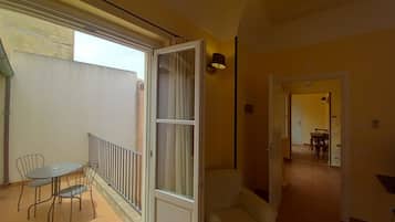 A spacious living area with a balcony, a dining table with chairs, and a sofa.