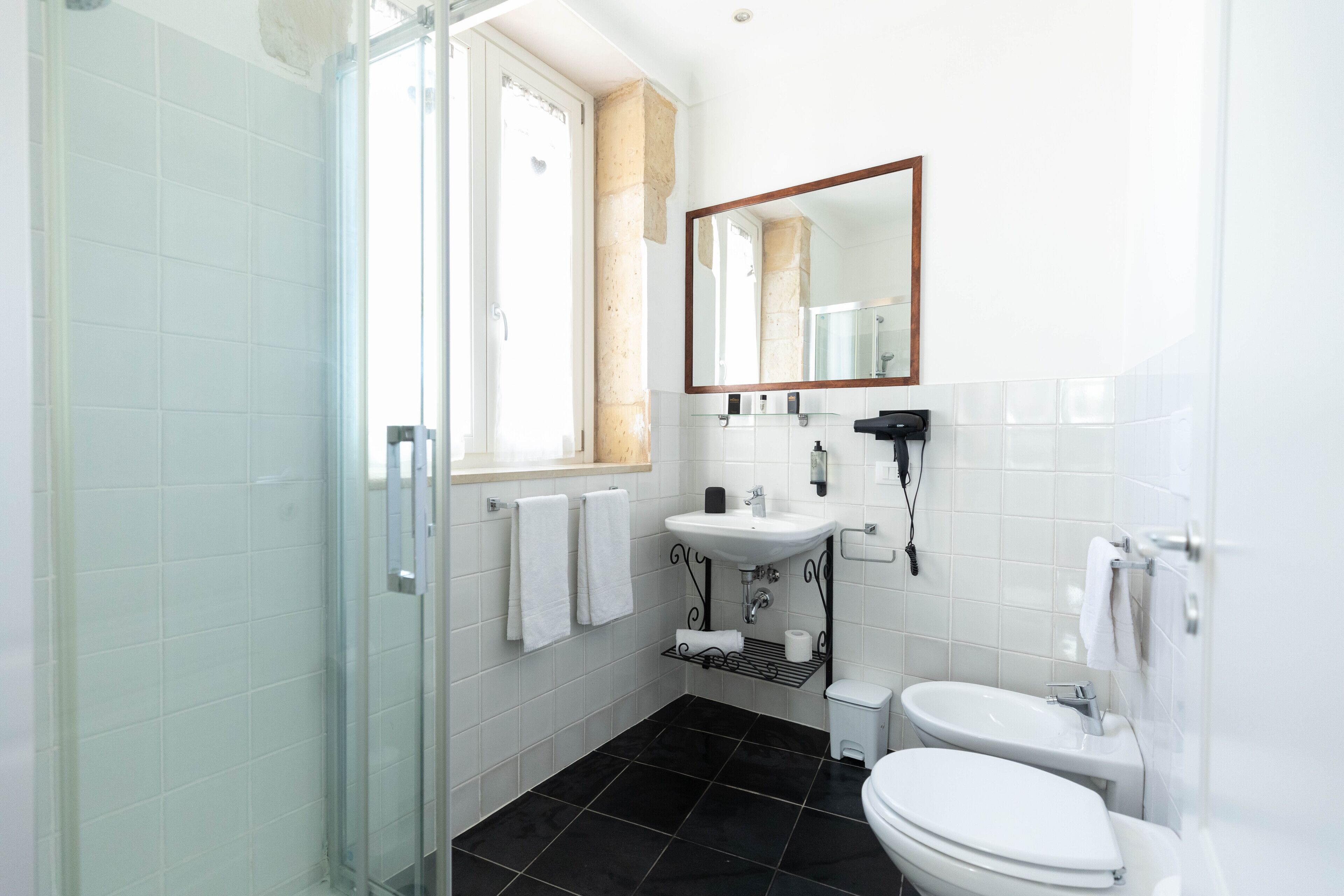 A modern bathroom with a glass shower enclosure, a sink, a toilet, and a large mirror.