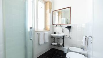 Une salle de bain moderne avec une douche à parois de verre, un lavabo, des toilettes et un grand miroir.