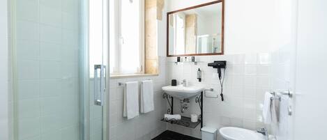 A modern bathroom with a glass shower enclosure, a sink, a toilet, and a large mirror.