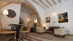 A spacious living area with a round table, wicker chairs, a striped rug, and a sofa. - Lanterne Magiche Ortigia (Syracuse)