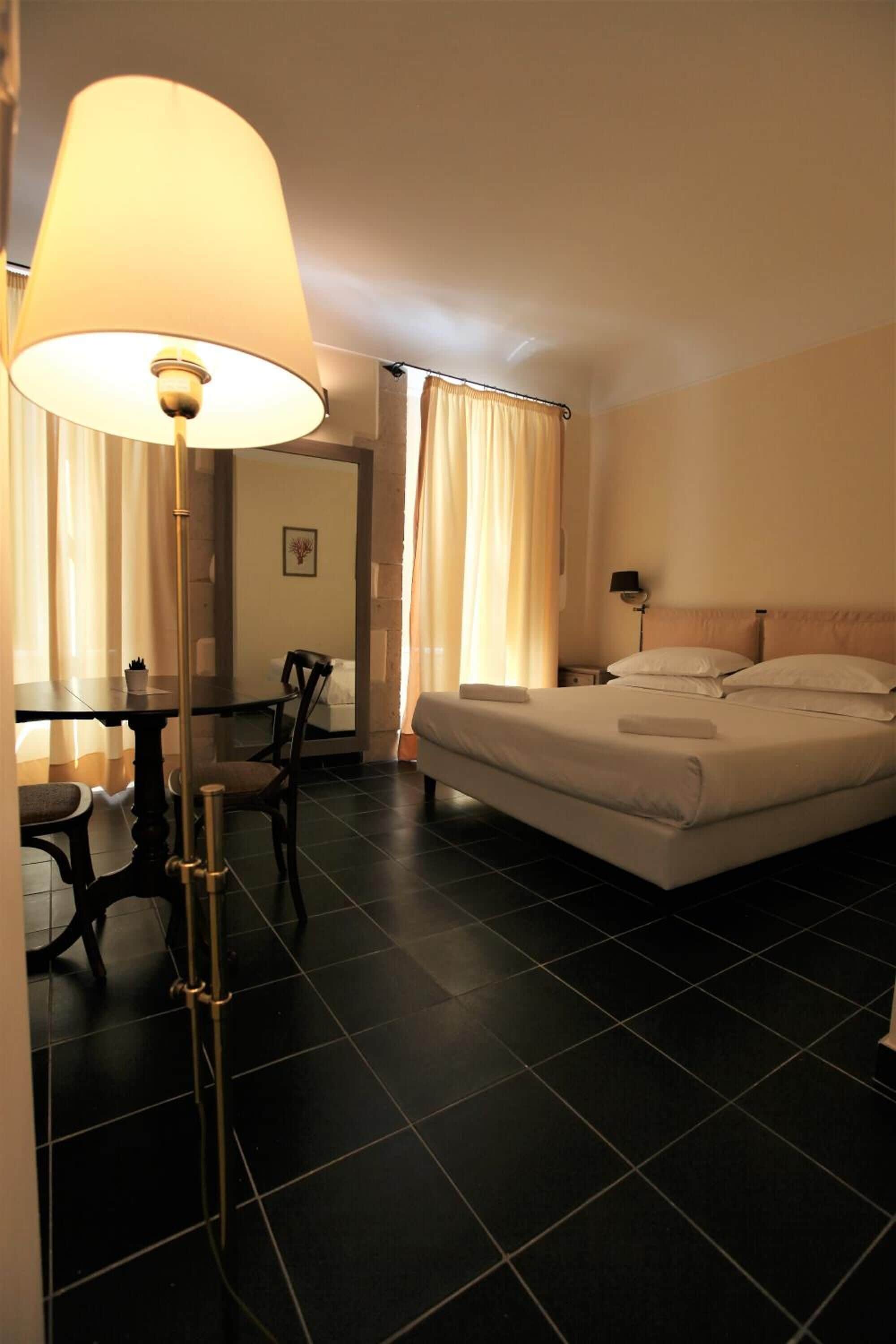 Una habitación de hotel con cama, escritorio, silla y lámpara.