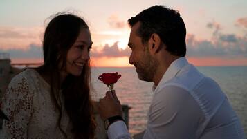 A couple holding a rose against a sunset backdrop.