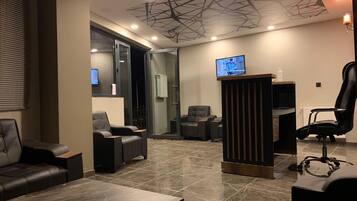 A modern interior with a reception desk, seating area, and a television screen.