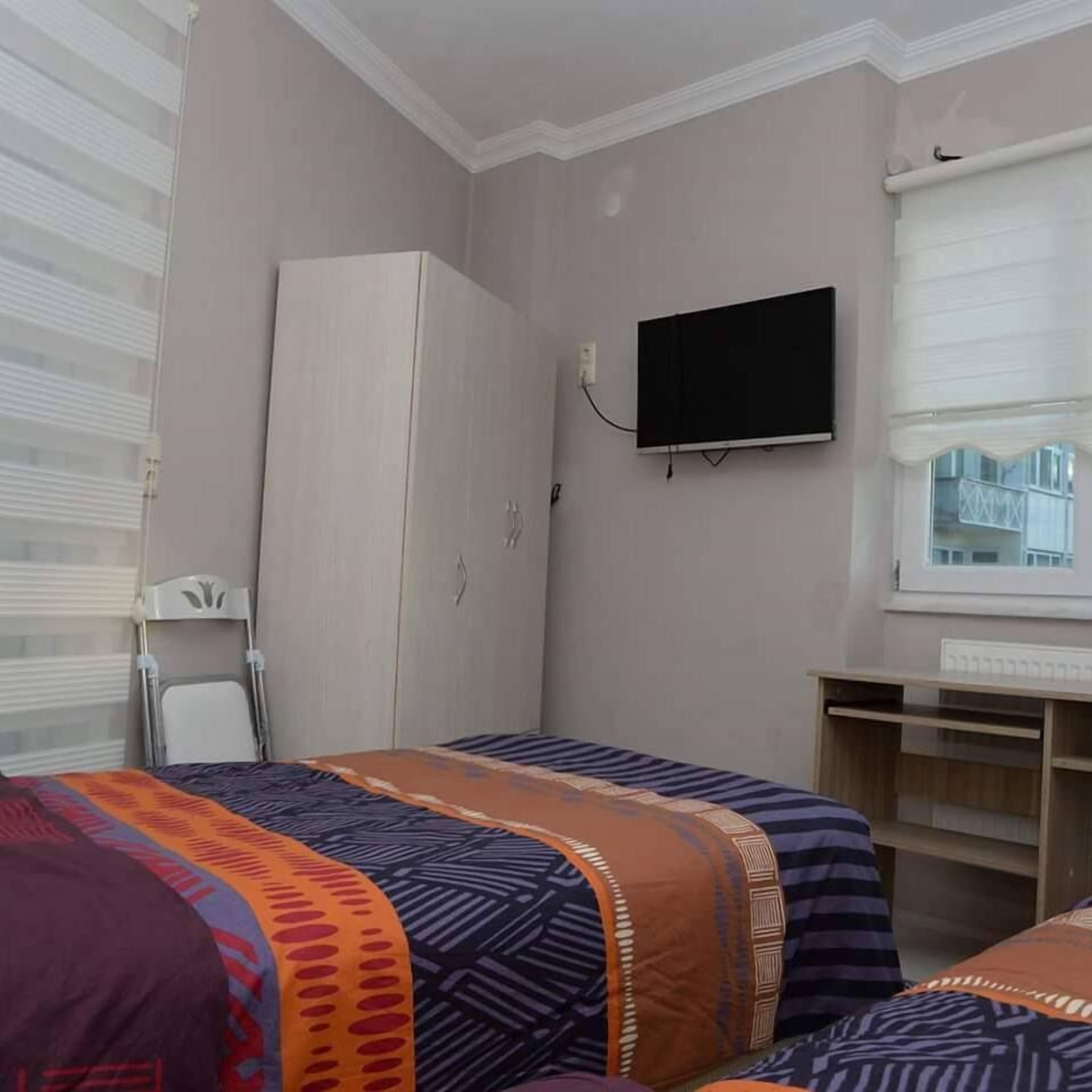 Un dormitorio con cama, armario, televisor y ventana con persianas.
