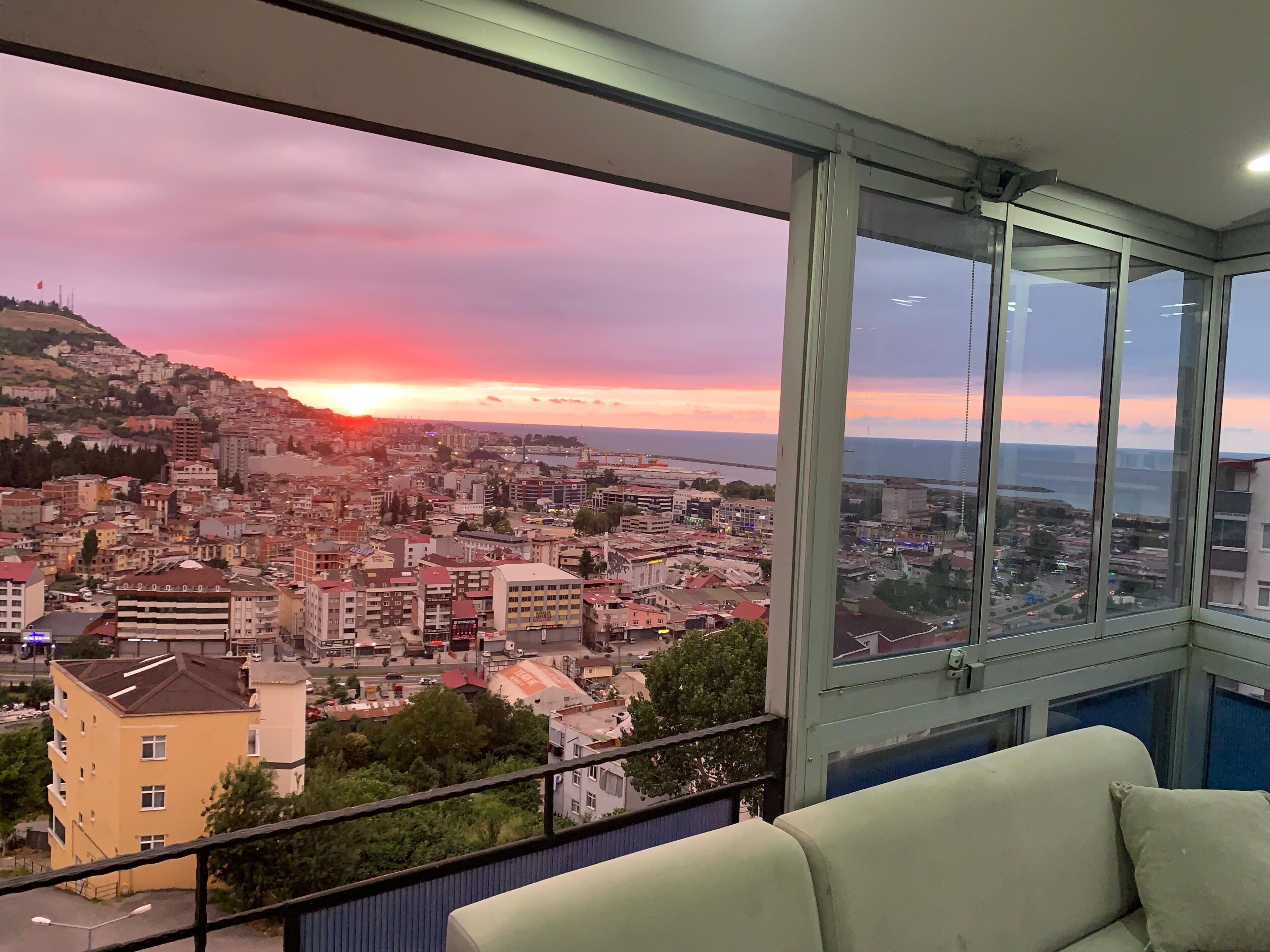 Une pièce dotée d’une grande fenêtre donnant sur un paysage urbain au coucher du soleil.