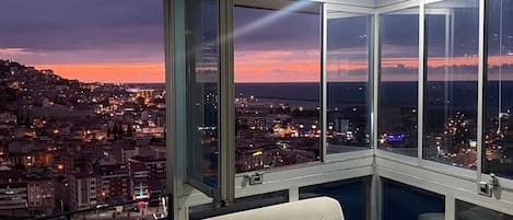 A high-rise room with a city view, a sofa, and a large window.