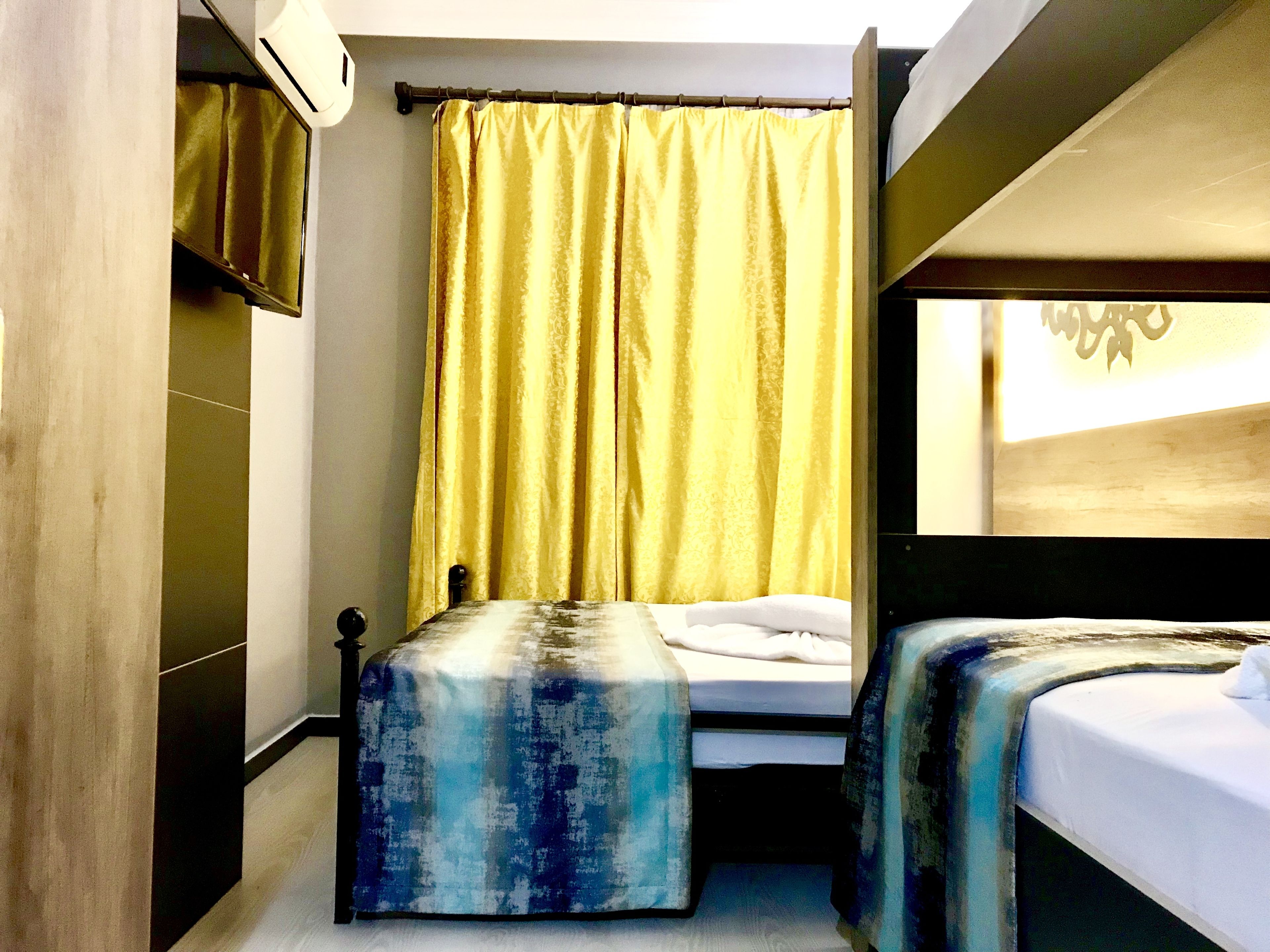 A hotel room with two beds, a large window, and a curtain.