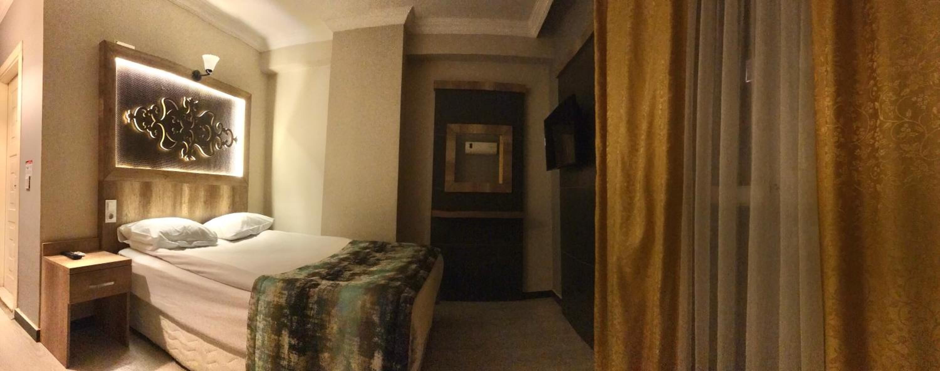 A hotel room with a bed, bedside table, and a decorative wall piece.