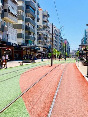 A tram track with a green and red running surface, surrounded by multi-story buildings with balconies and storefronts. - Otel Star Palace (Antalya)