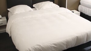 Un lit bien fait, avec du linge de lit blanc, dans une chambre d'hôtel.