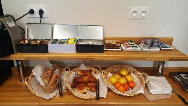 Un buffet de petit-déjeuner proposant du pain, des viennoiseries et des fruits.