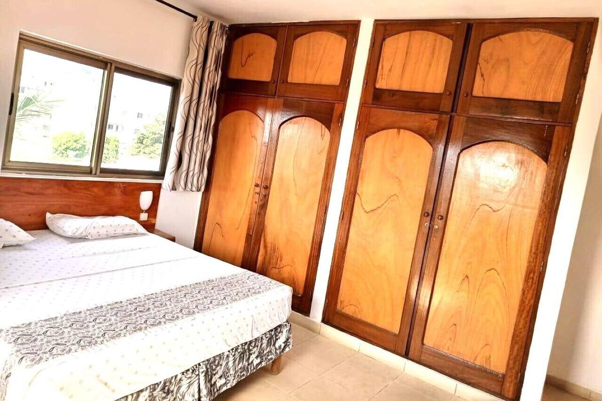 A bedroom with a bed, a window, and wooden wardrobe doors.