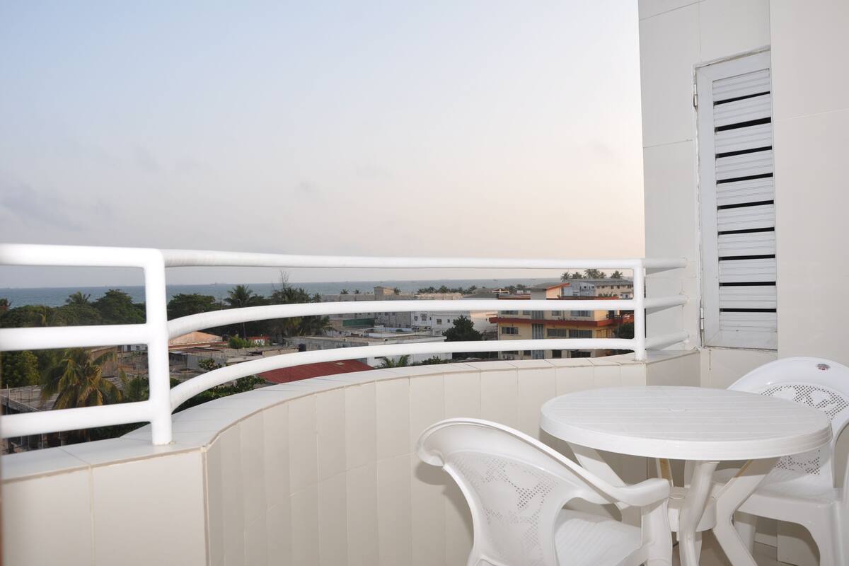 A balcony with a white railing, a small round table, and two white chairs.
