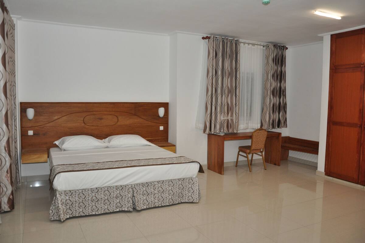 A bedroom with a wooden bed, a desk, and a chair.