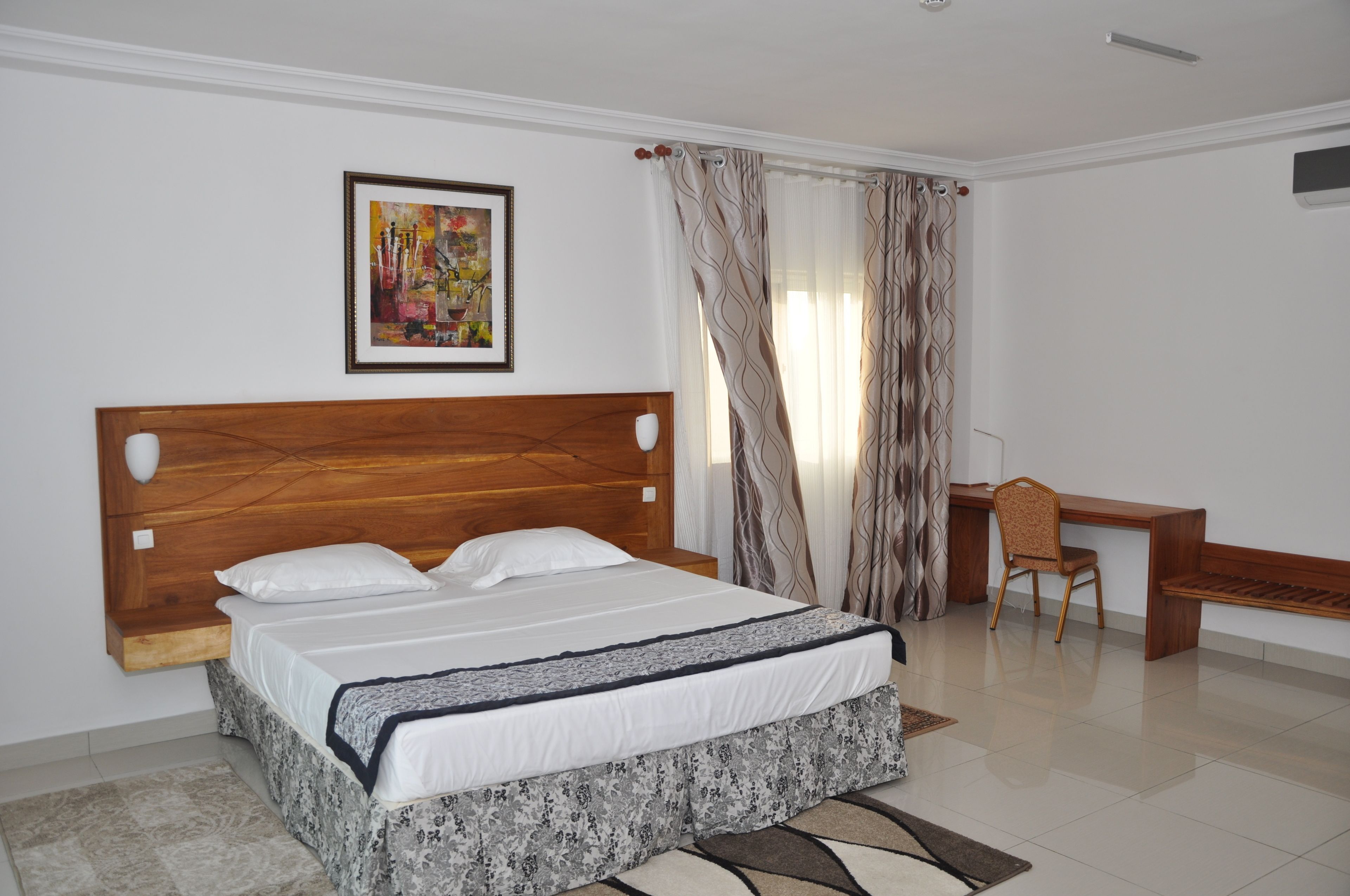 Un dormitorio ordenado con una cama de cabecera de madera, un escritorio y una silla.