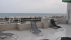 Un balcon avec trois chaises longues et vue sur la plage.