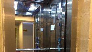 An elevator with metallic walls and a control panel with illuminated buttons.