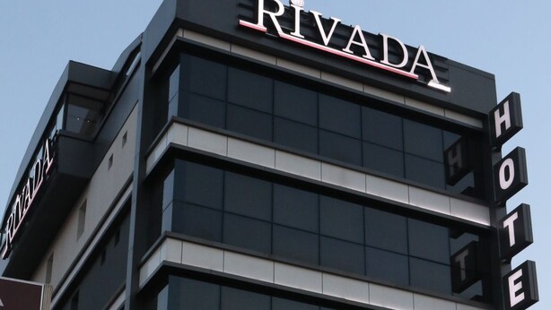 A hotel named RIVADA with a modern facade, a visible bank ATM, and a sign indicating Turkish currency.