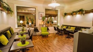 A modern hotel lobby with wooden flooring, green and black seating, and potted plants. - H5 Hotel (Helsingborg)