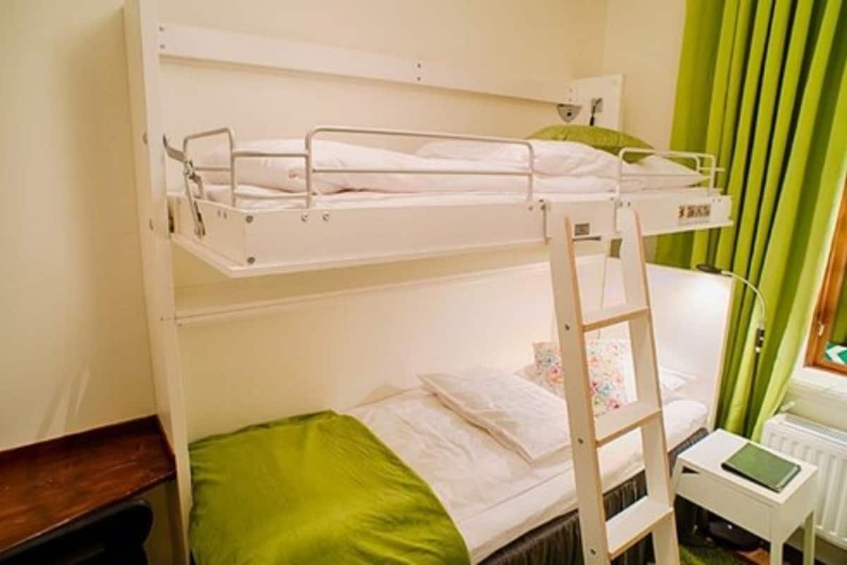 A bunk bed room with a ladder, a small table, and a radiator.