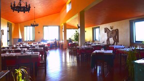 A spacious dining area with multiple tables and chairs, large windows allowing natural light, and a chandelier hanging from the ceiling. - Francalancia Country Resort (Castelnuovo di Porto)