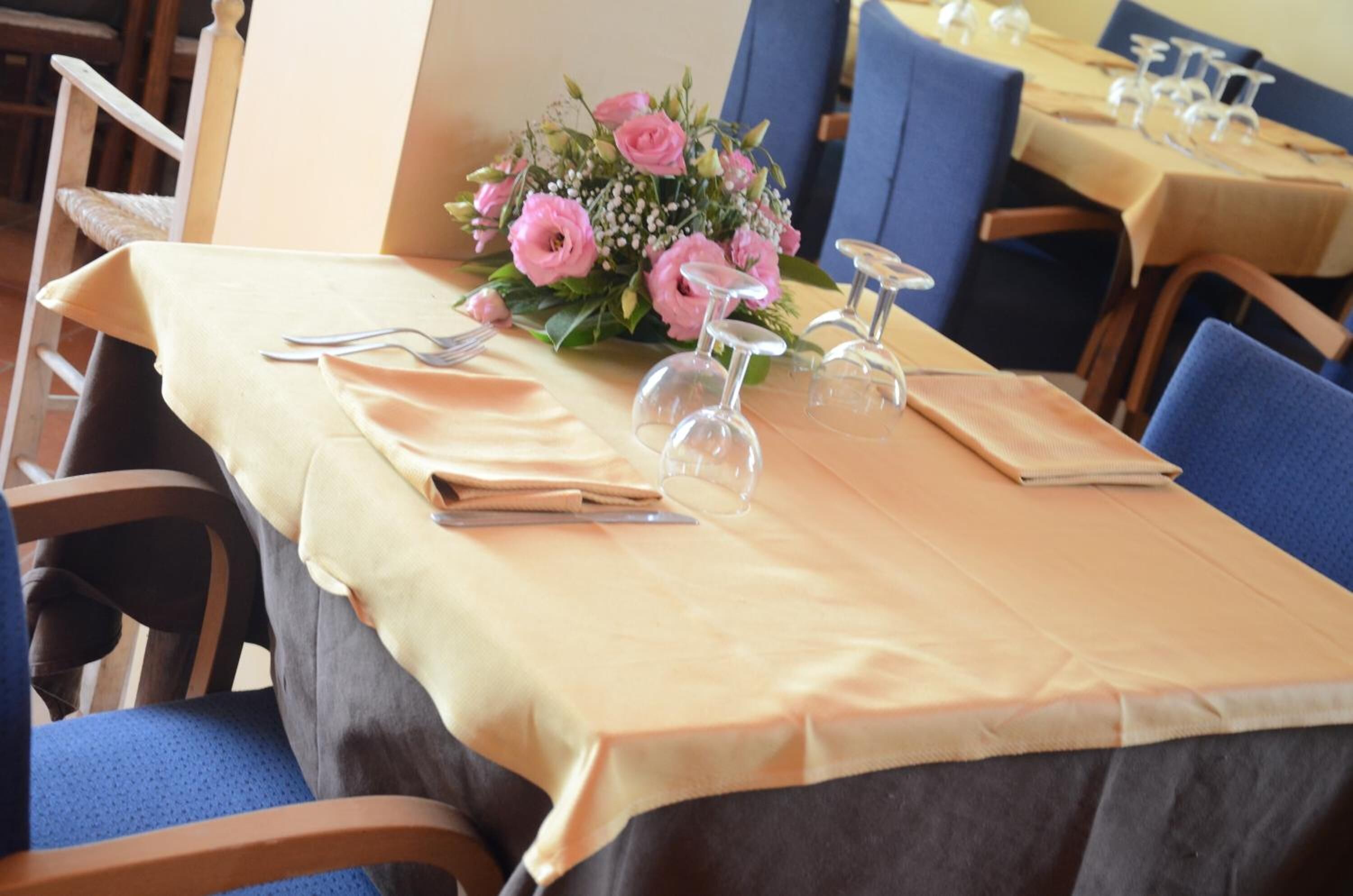 Una mesa de comedor dispuesta con mantel, sillas, un centro de mesa floral y cubiertos.