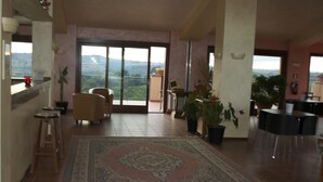 A spacious living area with a large rug, a dining table, chairs, and potted plants. - Francalancia Country Resort (Castelnuovo di Porto)