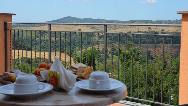 A balcony with a table set for breakfast overlooking a hilly landscape. - Francalancia Country Resort (Castelnuovo di Porto)