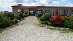 A building with a gravel driveway leading to a front door, surrounded by well-maintained gardens and shrubs. - Francalancia Country Resort (Castelnuovo di Porto)
