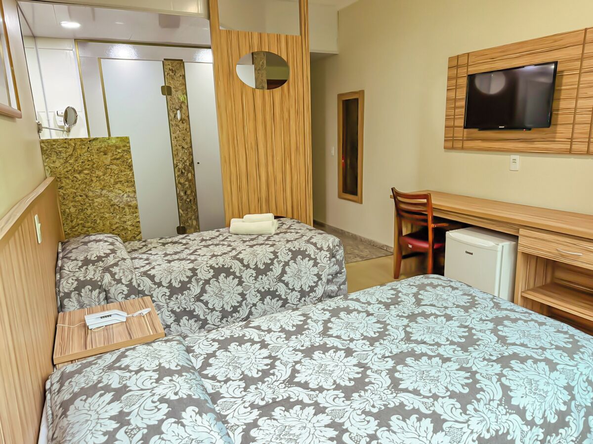 Une chambre d’hôtel avec deux lits, une télévision, un bureau et un petit réfrigérateur.