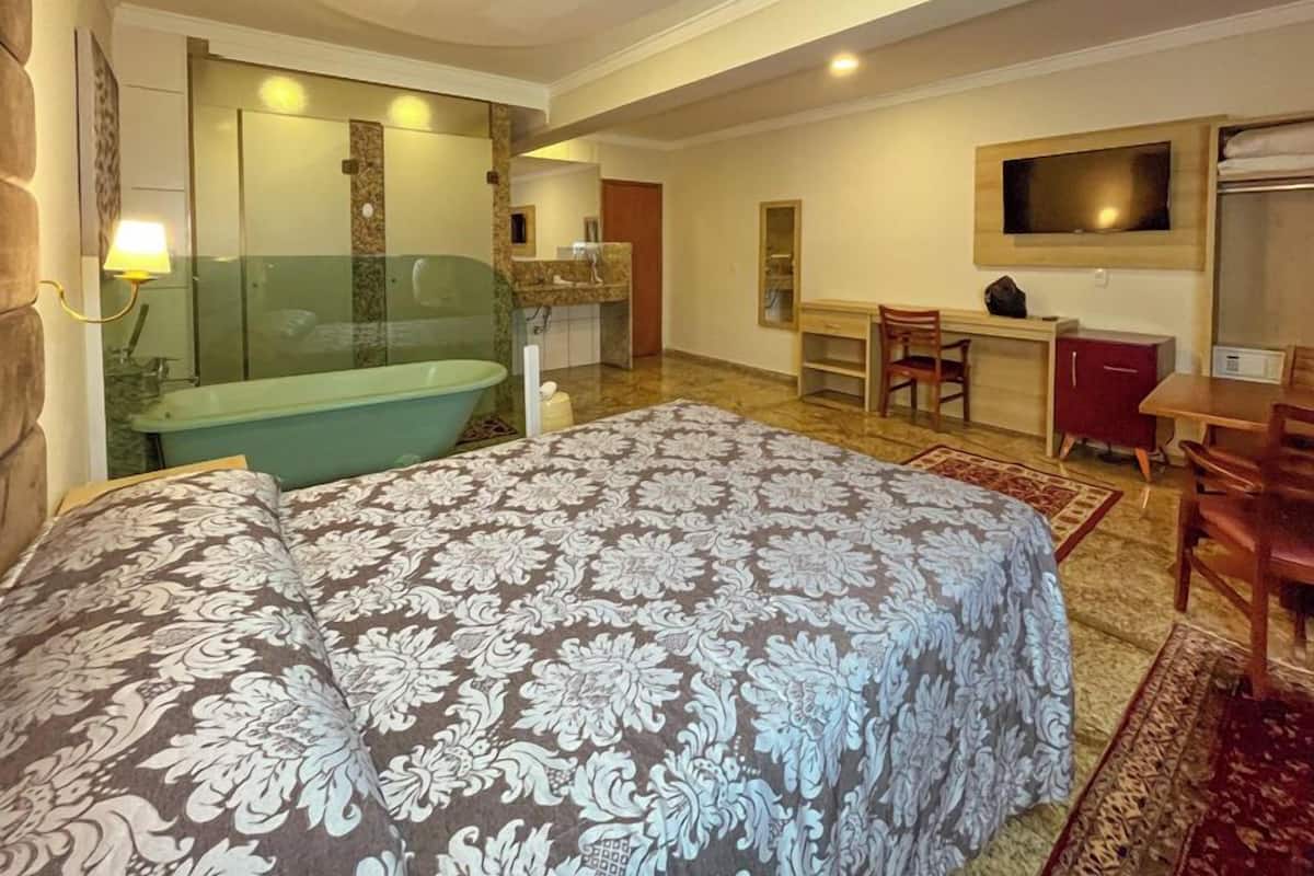 Een hotelkamer met een groot bed, een badkamer met een bad, een bureau en een televisie.
