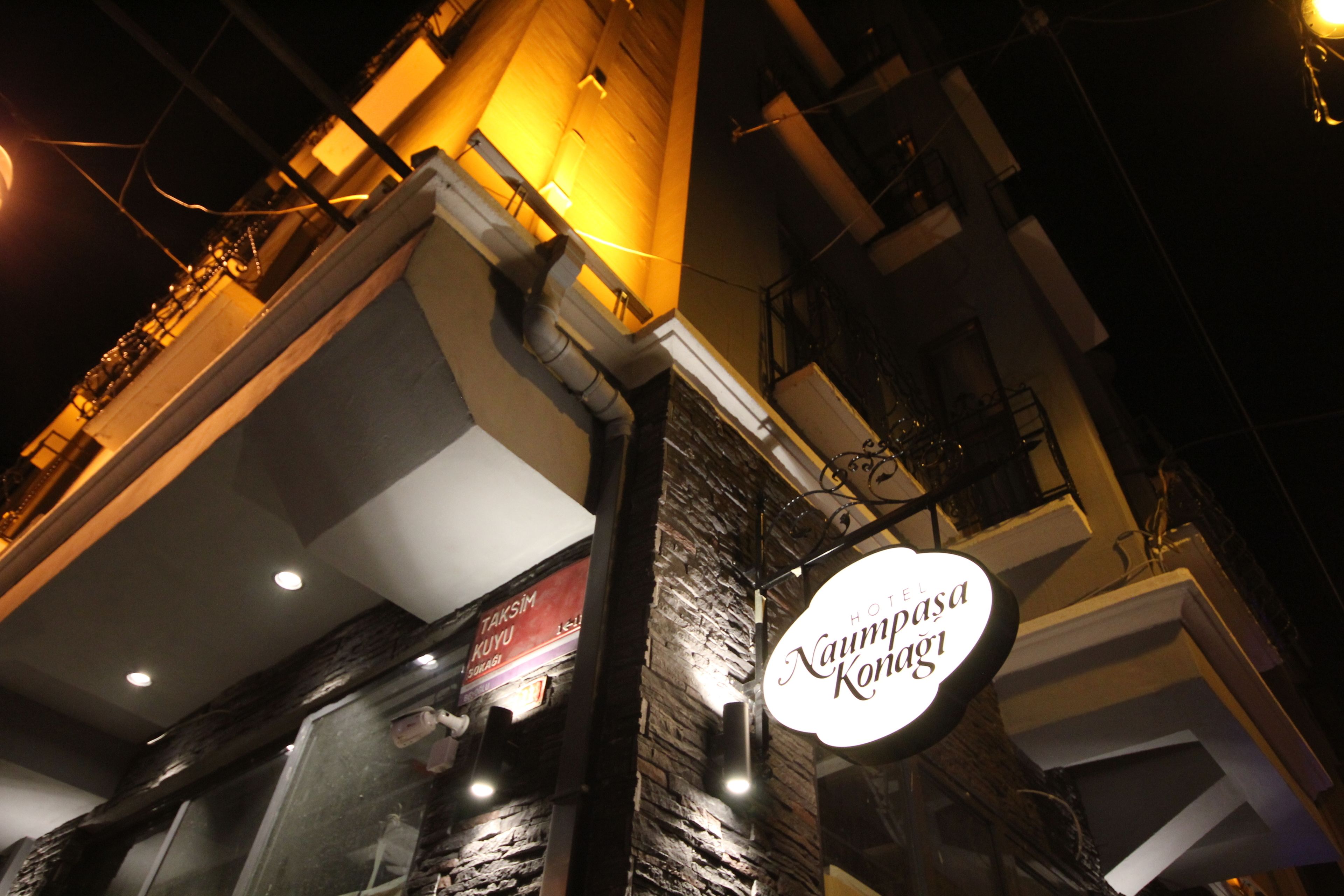 A hotel sign with the name "Naumpa Konagai" against a building facade with stone cladding and a glass window.