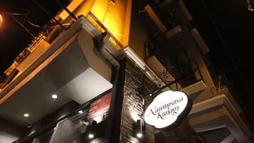 A hotel sign with the name "Naumpa Konagai" against a building facade with stone cladding and a glass window.