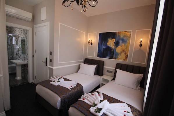 Quarto de hotel com duas camas, banheiro e uma grande pintura abstrata na parede.