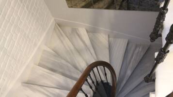 A spiral staircase with a wooden handrail and black balusters.
