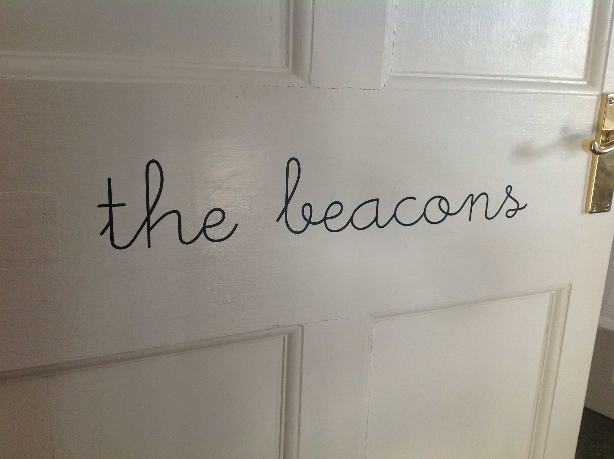 Una puerta blanca con la palabra "the beacons" escrita en cursiva negra.