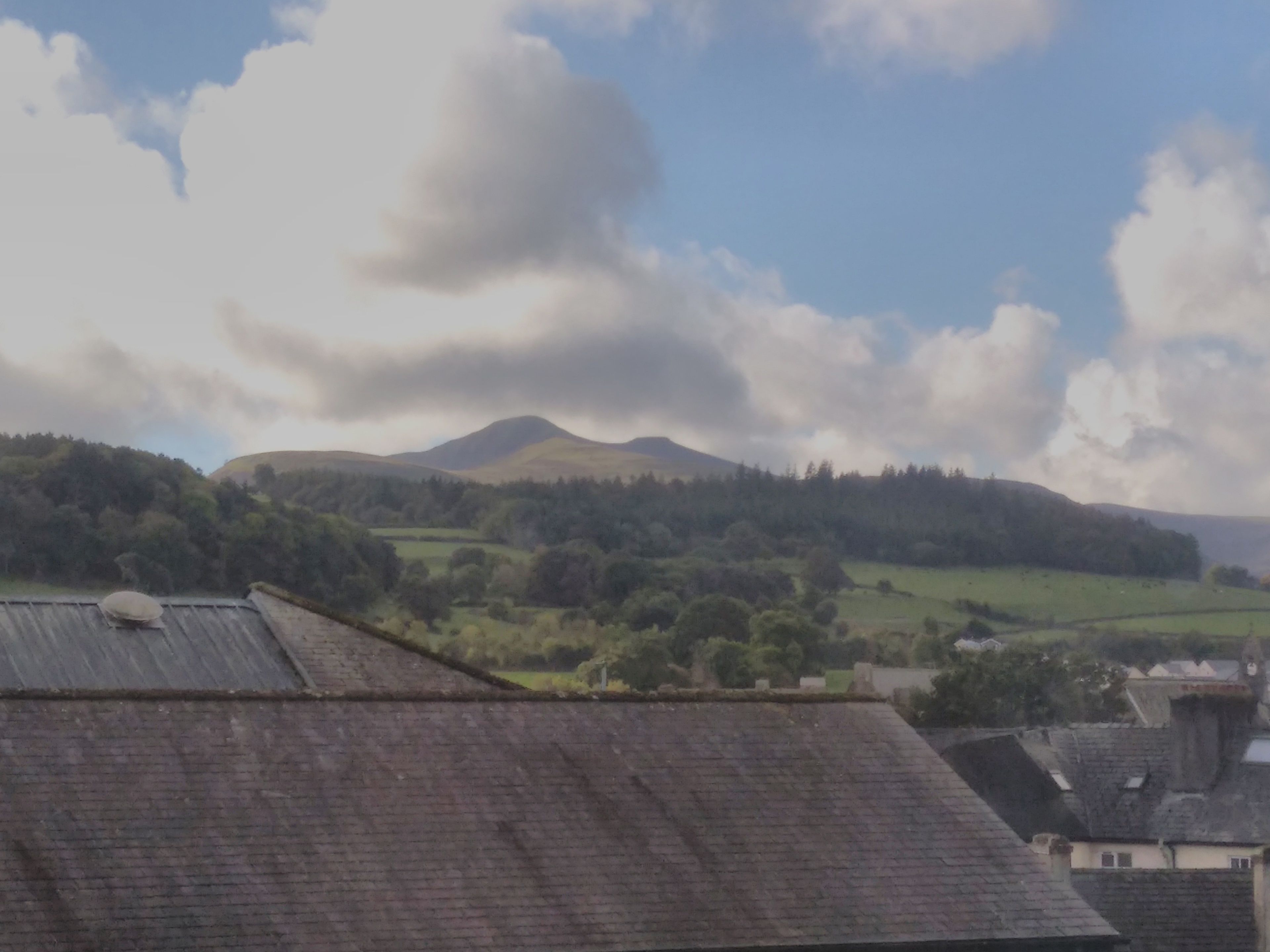 A view of a rural landscape with rolling hills and a mountain in the distance.