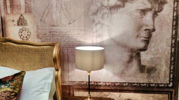 Una habitación con una cama, una lámpara en una mesita de noche y una obra de arte grande en la pared.