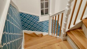 A staircase with wooden steps and white railings, leading to a room with a window and patterned blue and white walls. - Town House at Brecon (Brecon)