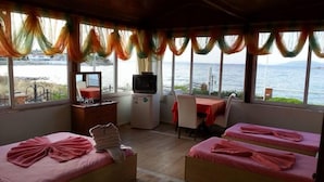 Una habitación con dos camas, un escritorio pequeño con televisión y vista al mar.