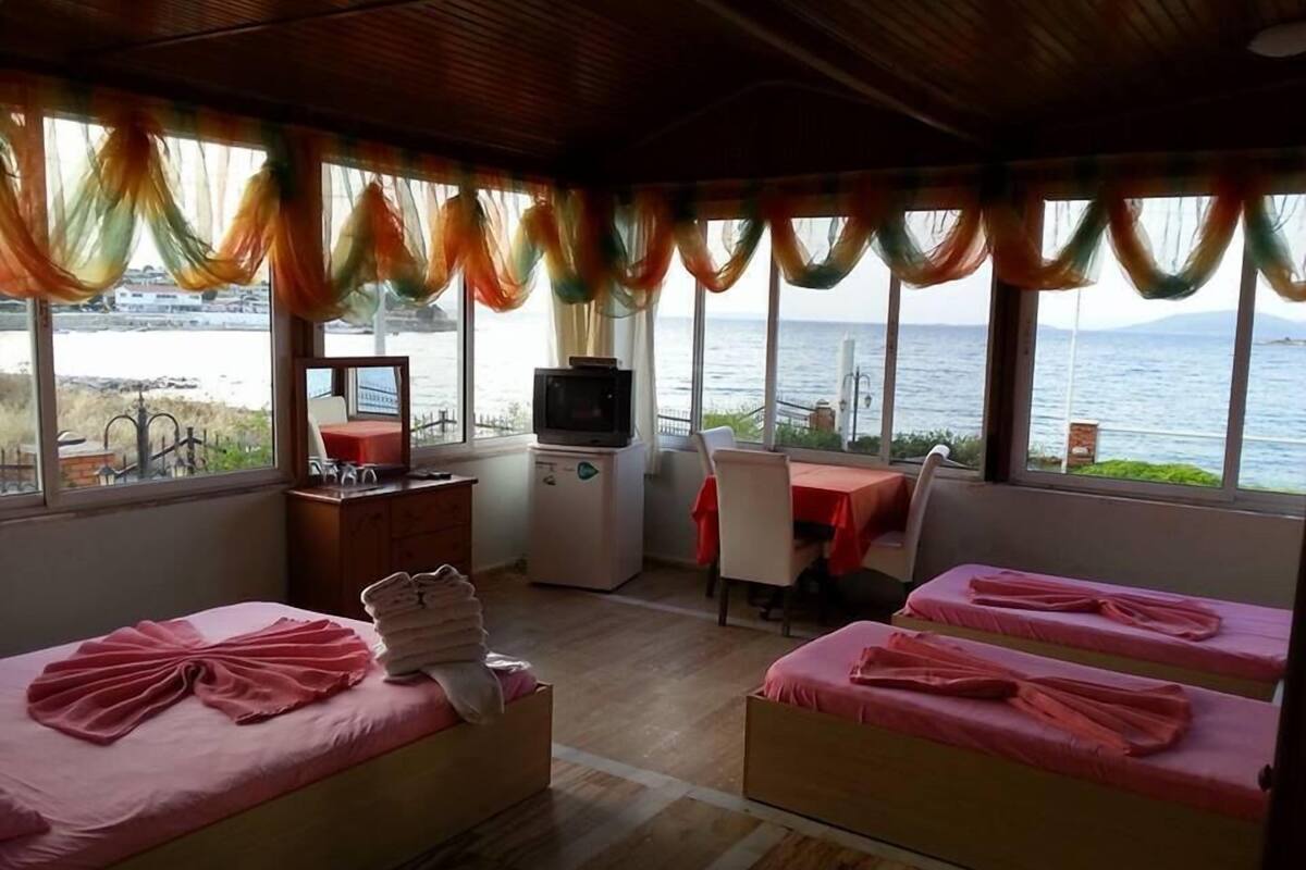 A room with two beds, a small desk with a TV, and a view of the sea.