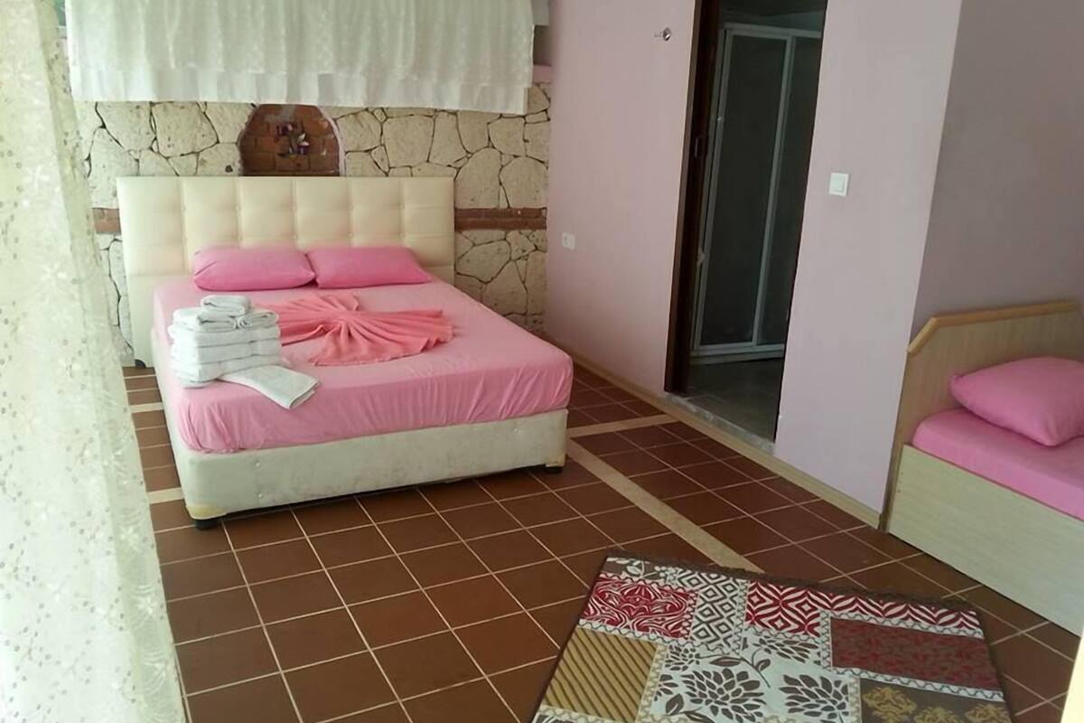 A bedroom with a bed, a small table, and a chair.