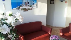 Una habitación con un sofá rojo, una mesa de centro y una pared con un cuadro azul y blanco.
