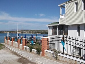 Un edificio costero con balcón, vistas al mar y un paseo pavimentado.